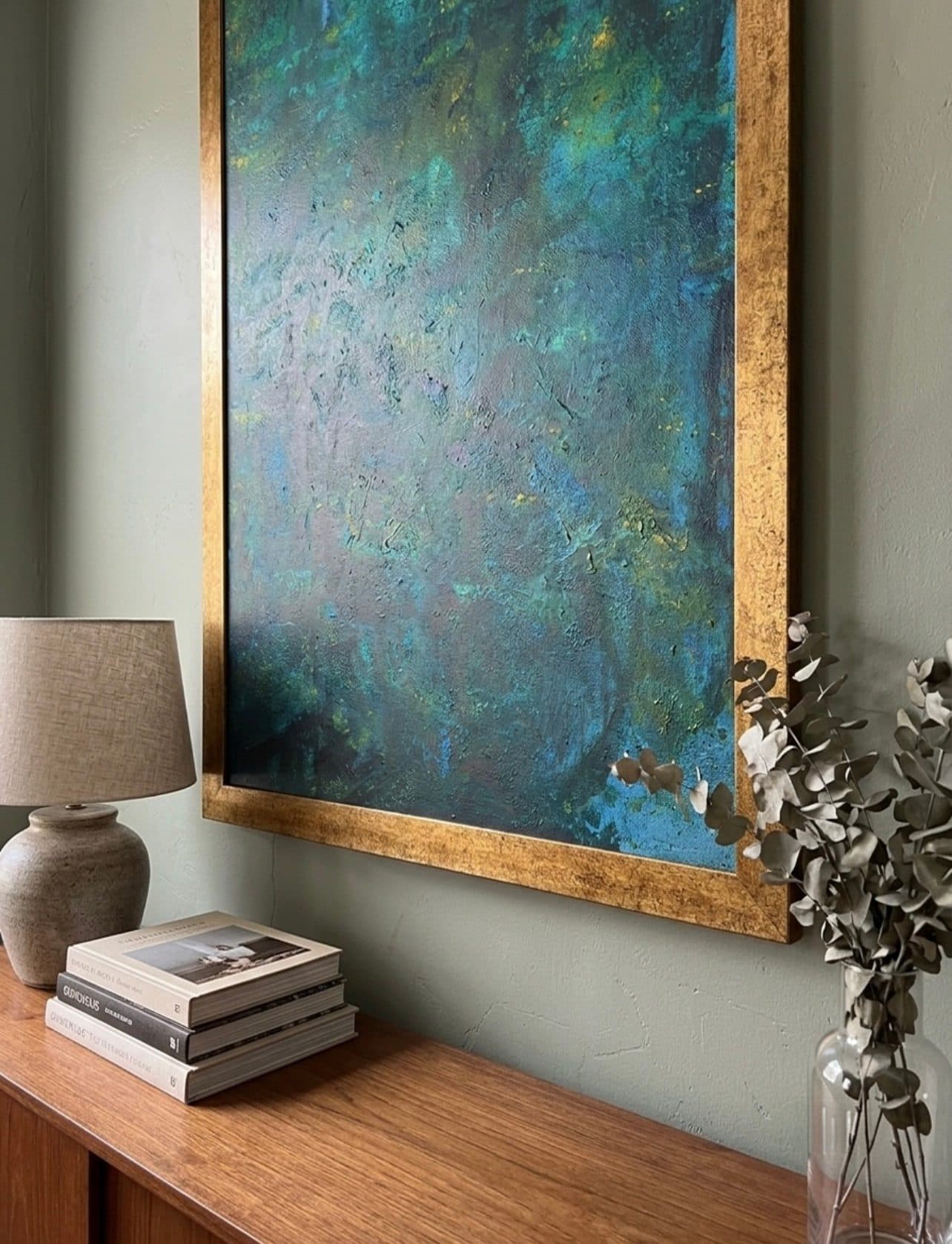 Emerald Drift im Goldrahmen über einer Holzkonsole mit Lampe und Eukalyptus